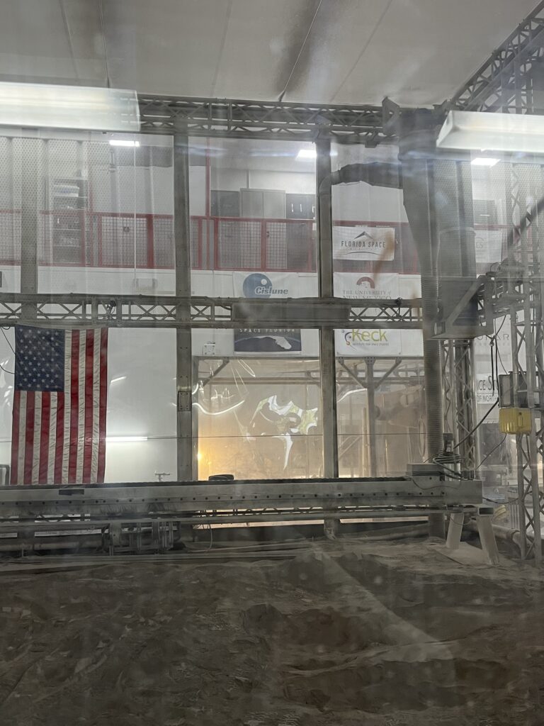 KSC Swampworks regolith bin with Cislune logo behind