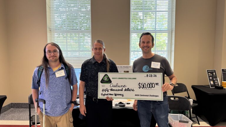 Three members of the Cislune team hold the NASA LunaRecycle Challenge Highest Mass Efficiency prize check in Tuscaloosa, Alabama.